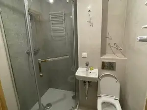 Wąska łazienka w bloku po remoncie z narożną kabiną, umywalką, WC podwieszanym i płytkami w kolorze betonu