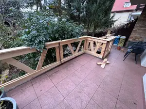 Nowa drewniana barierka zamontowana wzdłuż krawędzi tarasu z płyt przy domu jednorodzinnym