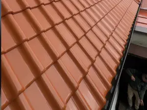 Okap dachu z dachówki ceramicznej po myciu, wzdłuż krawędzi rynna, pod okapem pracownik STmaster