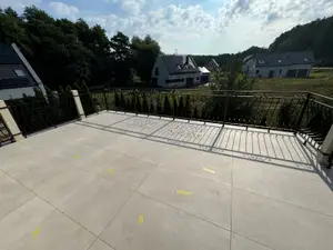 Taras z jasnych płyt gresowych z kutą balustradą, czysta nawierzchnia po zakończeniu prac